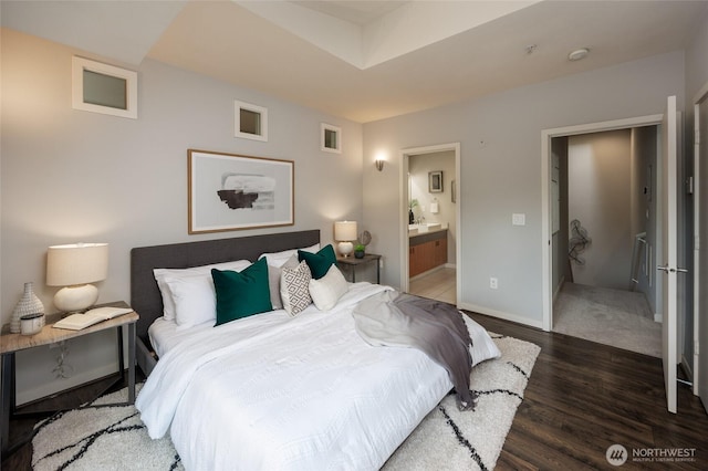 bedroom featuring ensuite bathroom, baseboards, and wood finished floors