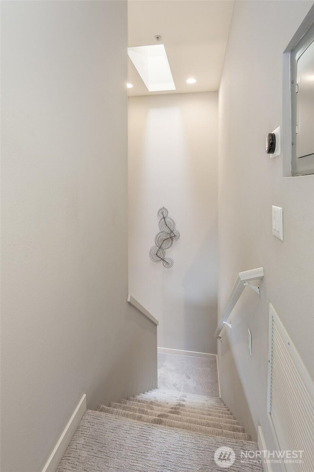 staircase featuring a skylight, baseboards, visible vents, and carpet flooring