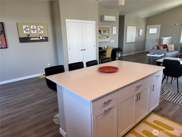 kitchen featuring light countertops, a breakfast bar, a wall mounted AC, and dark wood-style flooring