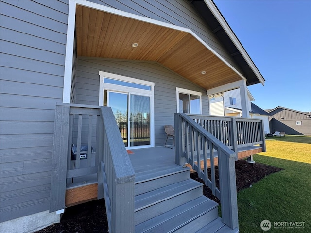 view of exterior entry with a deck and a yard