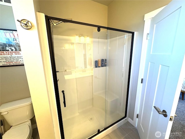 bathroom with toilet and a stall shower