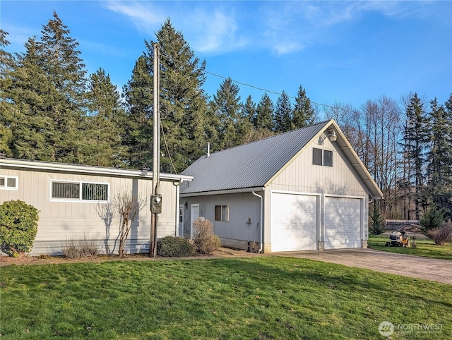 view of front of property with metal roof, a detached garage, and a front lawn