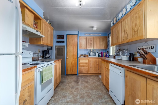 kitchen featuring white appliances, light countertops, stone finish flooring, and under cabinet range hood