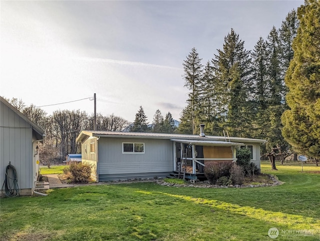 back of property with metal roof and a lawn