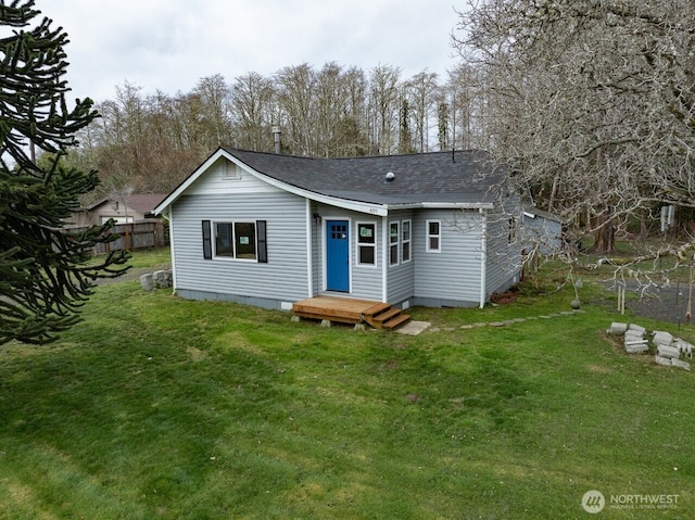 view of front of property featuring roof with shingles, a front yard, and fence