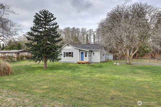 rear view of property featuring a yard and fence