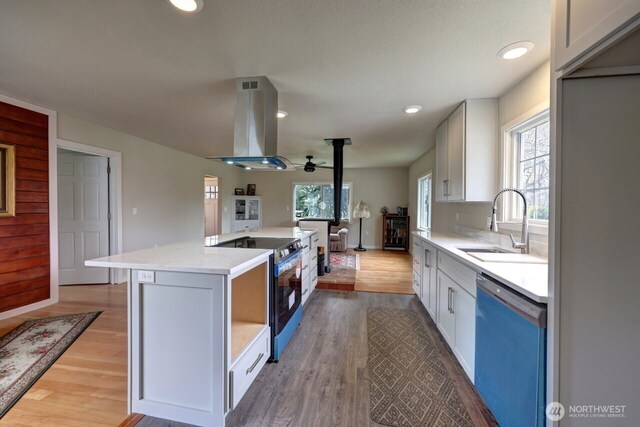 kitchen featuring range with electric stovetop, a kitchen island, a sink, island range hood, and dishwashing machine