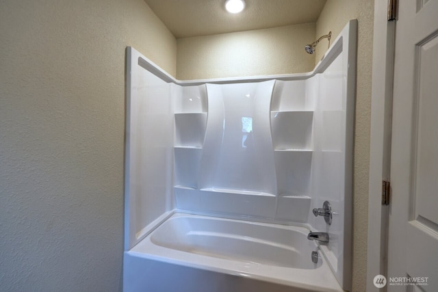 bathroom with a textured wall and shower / washtub combination