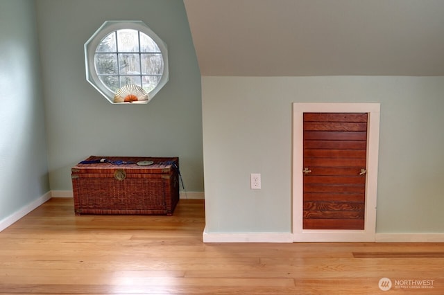 interior space featuring lofted ceiling, wood finished floors, and baseboards