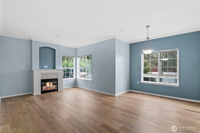 unfurnished living room with crown molding, a fireplace, baseboards, and wood finished floors