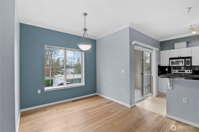 kitchen featuring light wood-style flooring, white cabinetry, dark countertops, stainless steel microwave, and plenty of natural light