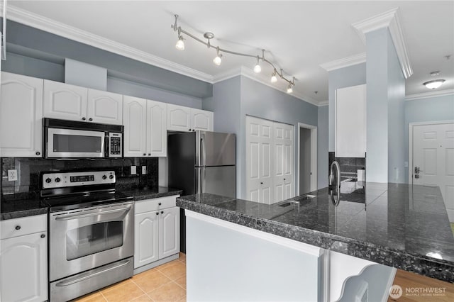 kitchen with tile countertops, stainless steel appliances, backsplash, ornamental molding, and white cabinets