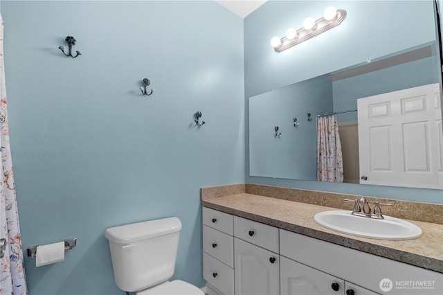 bathroom with curtained shower, vanity, and toilet