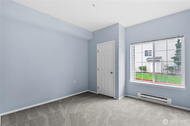 spare room featuring carpet floors, baseboards, and a baseboard heating unit