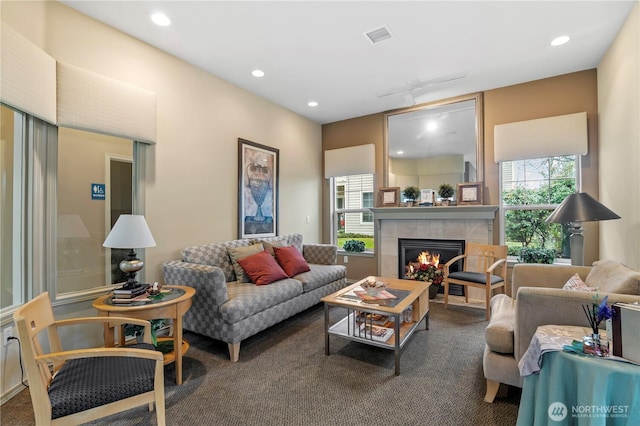 carpeted living room with track lighting, a tiled fireplace, visible vents, and recessed lighting