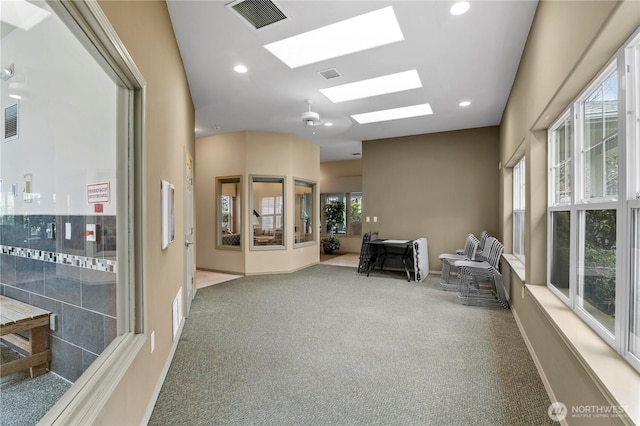 hallway featuring carpet, a skylight, visible vents, and recessed lighting