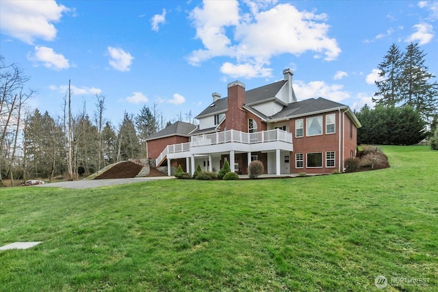 rear view of property with a lawn, driveway, and a chimney