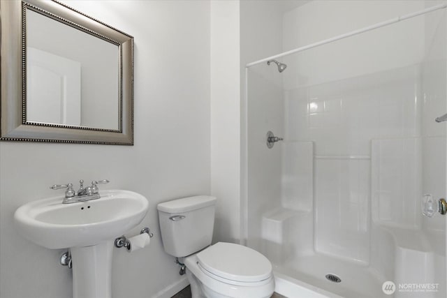 bathroom featuring walk in shower, toilet, and baseboards