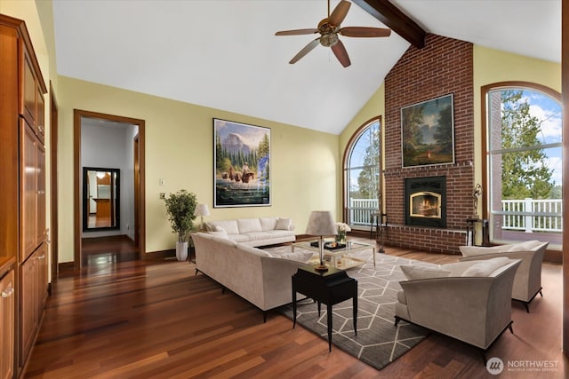living area with beamed ceiling, dark wood-style floors, a brick fireplace, high vaulted ceiling, and a ceiling fan