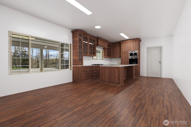 kitchen with light countertops, glass insert cabinets, dark wood-type flooring, and a sink