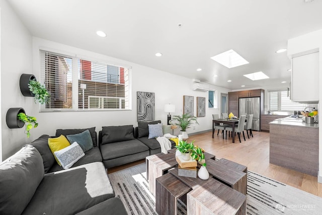 living area with light wood-type flooring, a skylight, recessed lighting, and a wall mounted AC