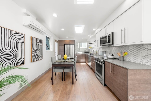 kitchen with tasteful backsplash, modern cabinets, appliances with stainless steel finishes, and an AC wall unit