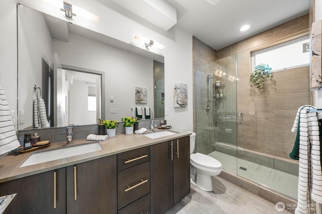 bathroom with double vanity, a stall shower, and a sink