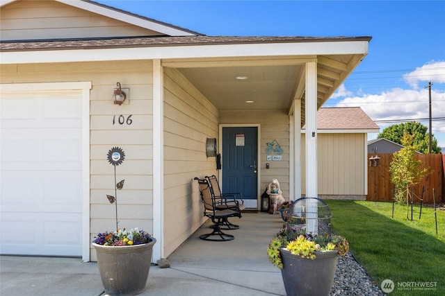 entrance to property with a garage, a yard, roof with shingles, and fence