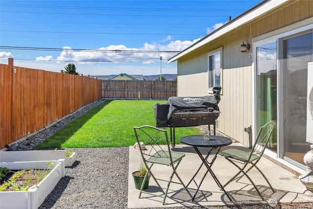 view of yard featuring a patio, a fenced backyard, and a garden