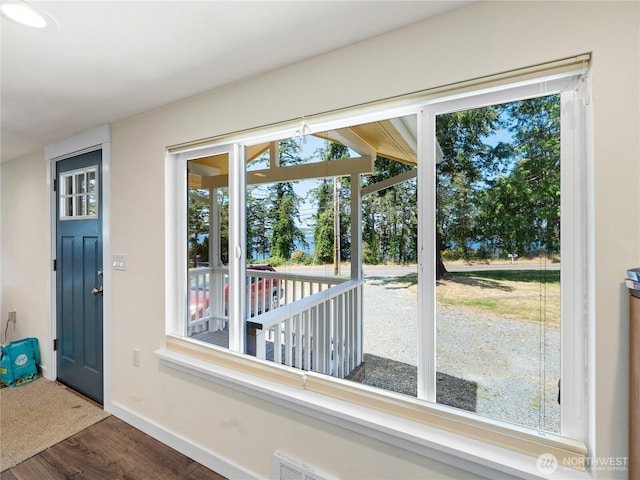 doorway with visible vents, baseboards, and wood finished floors