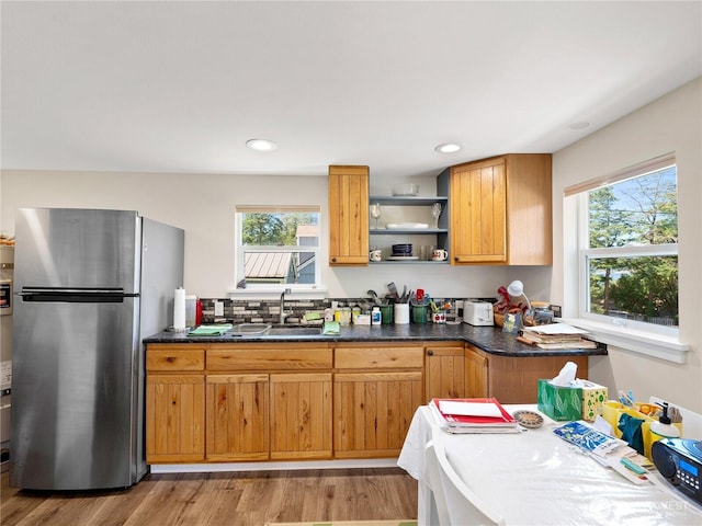 kitchen with wood finished floors, freestanding refrigerator, open shelves, a sink, and recessed lighting