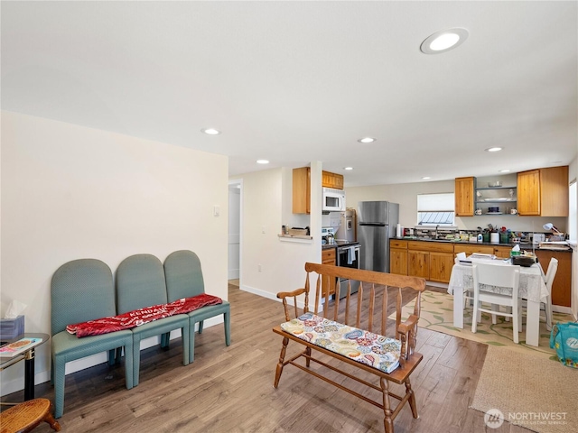 living room featuring baseboards, recessed lighting, and light wood-style floors