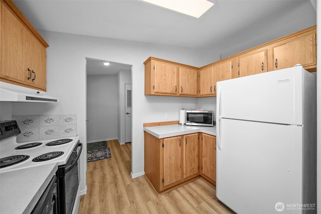 kitchen with light countertops, stainless steel microwave, electric range oven, freestanding refrigerator, and under cabinet range hood