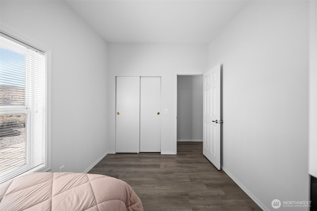 bedroom featuring dark wood-style floors, a closet, and baseboards