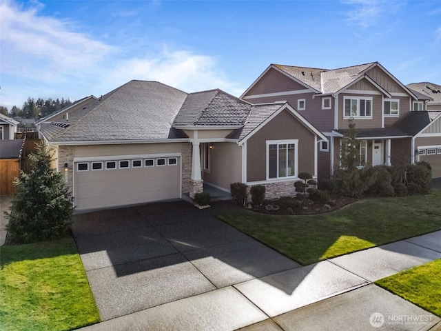 craftsman house with driveway, a front lawn, an attached garage, and stone siding