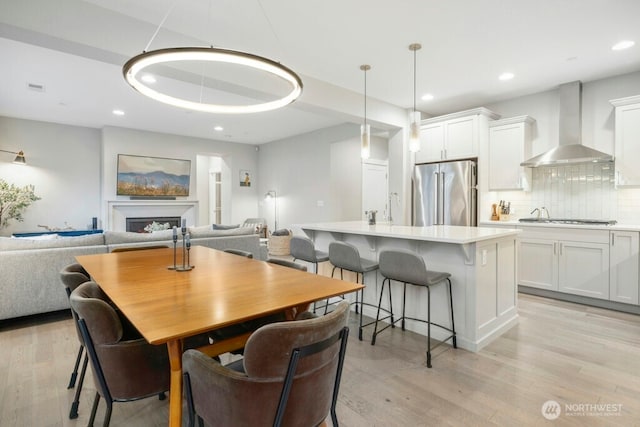 dining room with a fireplace, light wood-style flooring, and recessed lighting