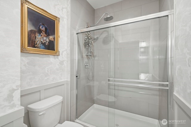 full bathroom featuring toilet, a shower stall, and wainscoting