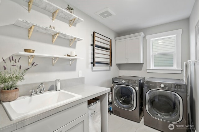 washroom featuring washing machine and dryer, cabinet space, a sink, and visible vents