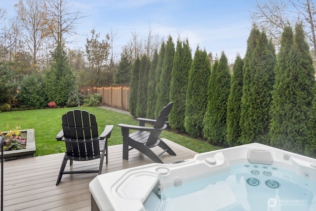 wooden deck featuring a lawn, fence, and a hot tub