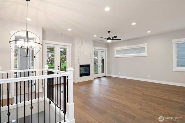 unfurnished living room with recessed lighting, french doors, wood finished floors, and ceiling fan with notable chandelier