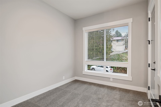 unfurnished room with dark colored carpet, baseboards, and a wealth of natural light