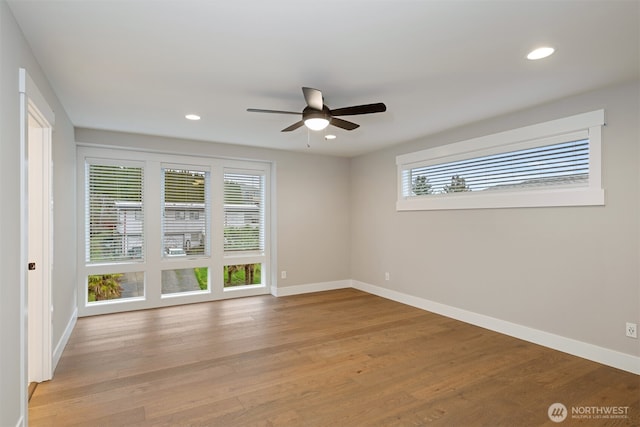 spare room featuring a wealth of natural light, recessed lighting, light wood-style flooring, and baseboards