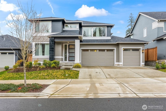 prairie-style home with a garage, driveway, and a shingled roof