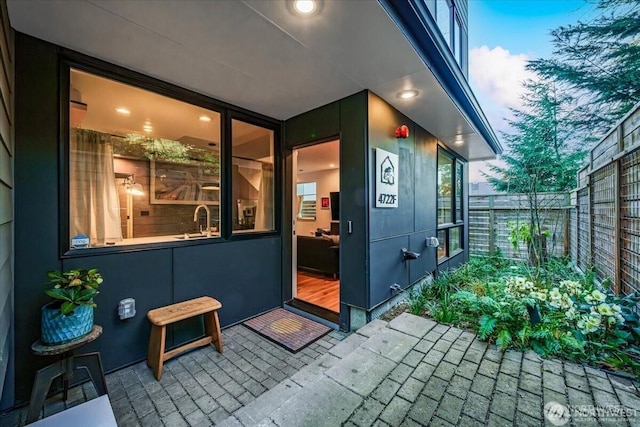 view of exterior entry featuring a patio area, fence, and a sink