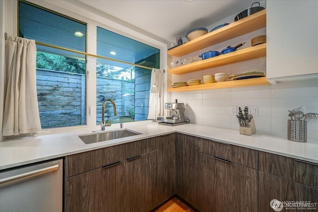 kitchen featuring tasteful backsplash, dark brown cabinetry, a sink, and stainless steel dishwasher