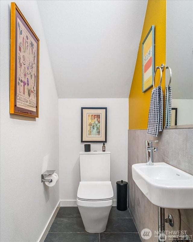 bathroom featuring tile patterned flooring, baseboards, lofted ceiling, and toilet