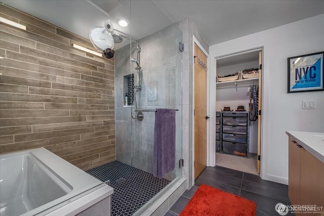 bathroom with a tub to relax in, a spacious closet, a stall shower, vanity, and tile patterned flooring