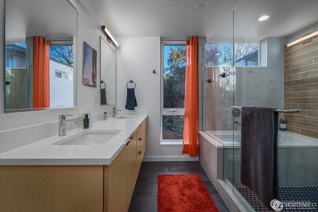 bathroom with double vanity, tiled shower, a sink, and tile patterned floors