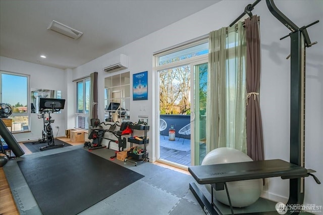 exercise area with recessed lighting, a wall mounted air conditioner, and a healthy amount of sunlight