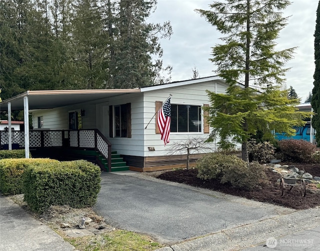 manufactured / mobile home featuring aphalt driveway and a carport